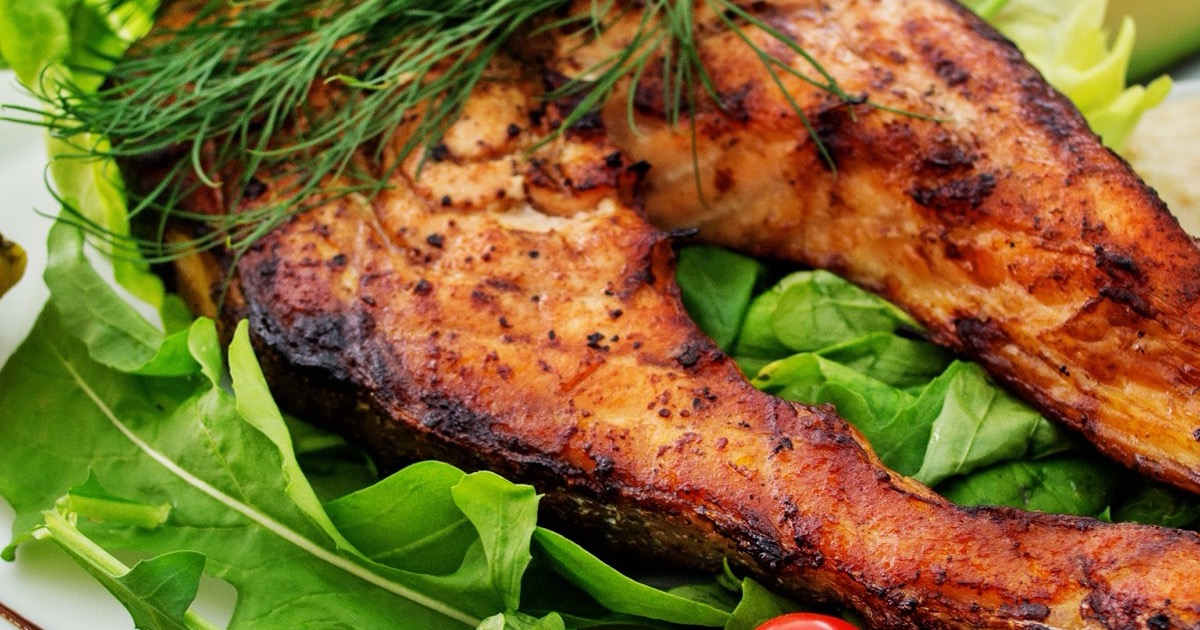 Grilled salmon steaks on a bed of salad greens, topped with fresh dill.